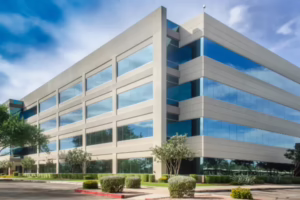 Exterior view of a multi-story modern commercial office building with large tinted glass windows.