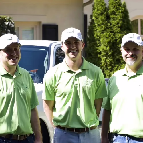 Three Mr. Mister Mosquito Control technicians standing in front a work truck and a residential house in Cherokee County